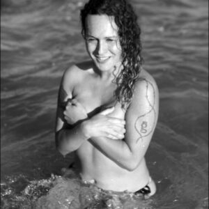 Trans female Nikki Montero sports curly brunette hair while totally naked in the ocean