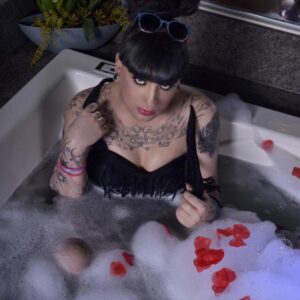 Tattooed shemale Kelly Clare takes off her ankle strap heels before getting in a tub
