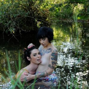 Dark-haired transsexual Mandy Mitchell and a tattooed girl kiss before upskirt action