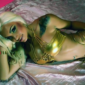 Platinum blonde TS Angeles Cid models a gold bathing suit during a SFW shoot